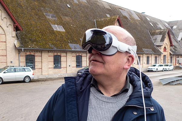 Thomas Hillerup med AR-briller på står foran Materialgaarden og kigger skråt op til venstre.