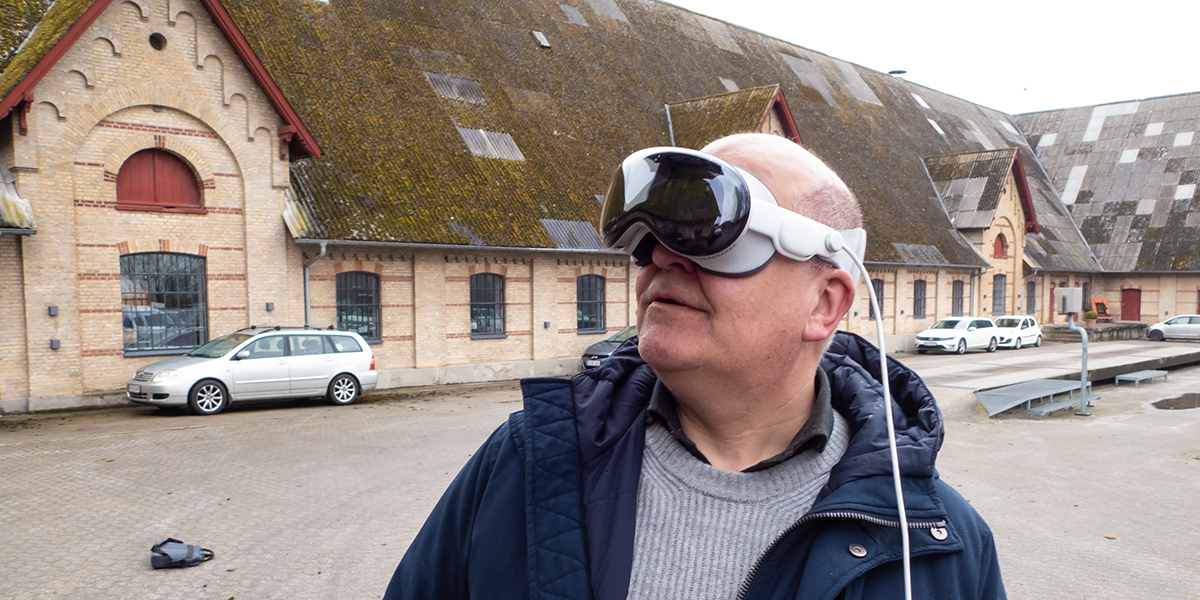Thomas Hillerup med AR-briller på står foran Materialgaarden og kigger skråt op til venstre.