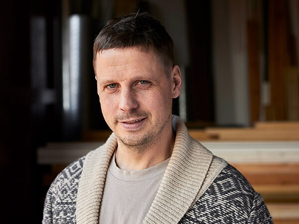 Portræt af Casper med træ og tømmer i baggrunden.