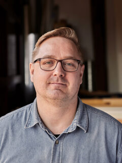 Portræt af Rasmus med træ og tømmer i baggrunden.