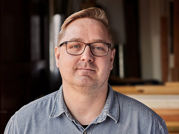 Portræt af Rasmus med træ og tømmer i baggrunden.